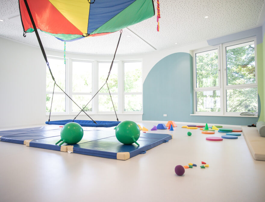 Bewegungsraum mit Nestschaukel, buntem Schwungtuch, Turnmatten und Gymnastikbällen